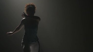 Kıvırcık kız stüdyoda spot ışığı capoeira performans. Yakın çekim yavaş çekim.