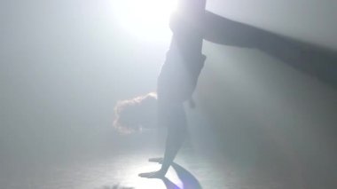 Yakın çekim yavaş çekim. Kıvırcık bakire stüdyoda spot ışığı capoeira pratik.