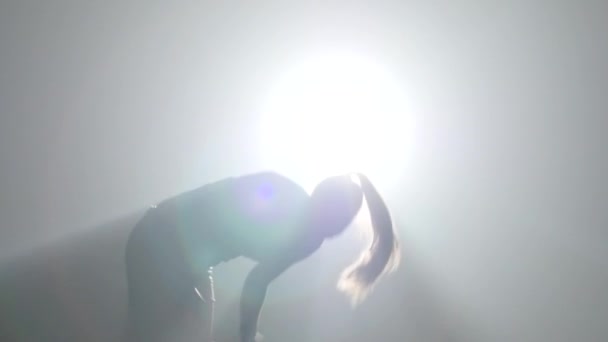 Girl practicing capoeira in ray of spotlight in studio. Close-up slow motion. — Stock Video