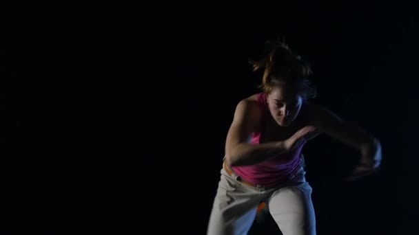 Primer plano, cámara lenta, mujer practicando capoeira en la oscuridad en el estudio — Vídeos de Stock