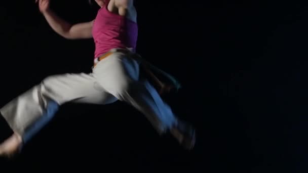 Nahaufnahme eines Mädchens, das Capoeira im Dunkeln im Studio praktiziert. Zeitlupe — Stockvideo