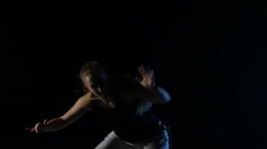 Uzun saçlı, karanlıkta capoeira uygulayan yakın çekim kadın. Yavaş çekim