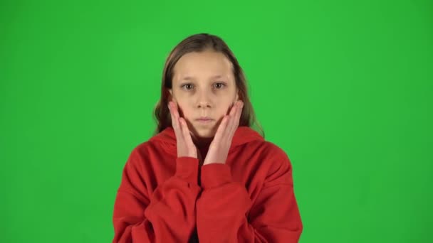 小さな女性は怖がって、緑の背景にスタジオで彼女の顔を隠しています. — ストック動画