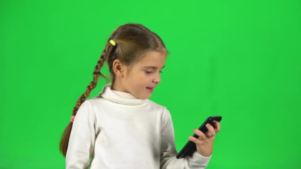 Menina conversando em vídeo conversando no telefone em estúdio contra tela verde — Vídeo de Stock