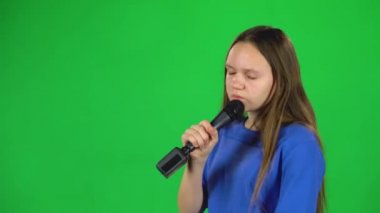 Küçük kadın stüdyoda yeşil ekranda mikrofona şarkı