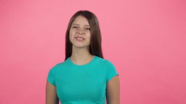 Genç kadın pembe arka plan üzerinde stüdyoda gülüyor. Yavaş çekim
