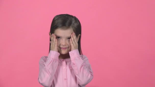 La pequeña hembra está escondiendo la cara con las manos en el fondo rosa. Movimiento lento — Vídeo de stock