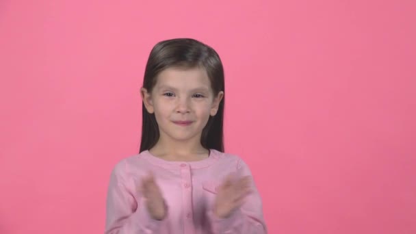 Szép lány tapsolt a kezét a rózsaszín háttér. Lassított mozgás — Stock videók