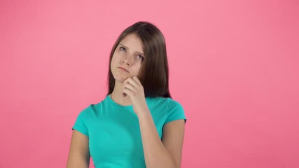 Kis nő gondol stúdióban rózsaszín háttér. Lassított mozgás — Stock videók