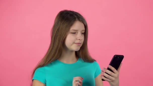 Девушка разговаривает на видео чате по мобильному телефону в студии на розовом фоне. Медленное движение — стоковое видео