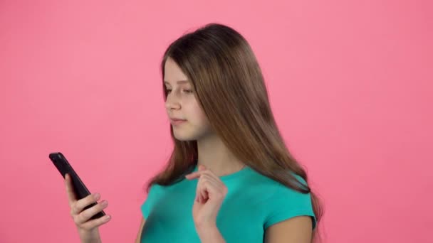 Gadis berbicara menggunakan ponsel di studio terhadap latar belakang merah muda. Gerakan lambat — Stok Video
