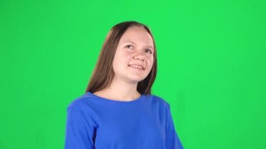 Yeşil arka planda kameraya bakan gülümseyen kız. Yavaş çekim
