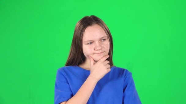 Little female is thinking in studio on green background. Slow motion — Stock Video