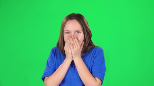 Děvče dospívající je vystrašené a skrývá její tvář ve studiu na zeleném pozadí. Zpomaleně — Stock video