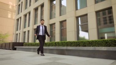 Mutlu işadamı ofis merkezi nin yakınındaki sokakta dans ediyor ve başarılarını kutlayan takım elbise giyiyor. Steadicam atış.