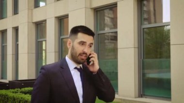 Akıllı telefonda konuşan duygusal gülümseyen genç adam. Heyecanlı işadamı cep telefonuyla konuşurken iyi haberleri duymaktan mutlu. Yakın çekim.