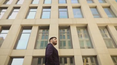 Mutlu işadamı şehir etrafında yürüyüş, modern bir binanın arka planda başarılı ve kendine güvenen adam.