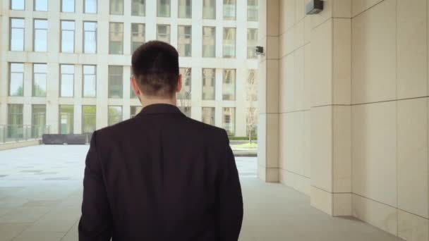 Hombre de negocios irreconocible caminando por la ciudad, hombre exitoso y seguro de sí mismo en el fondo de un edificio moderno. Vista trasera — Vídeos de Stock