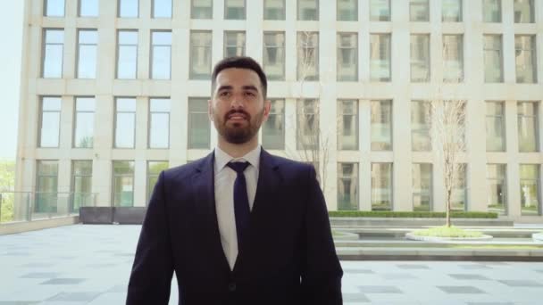 Feliz hombre de negocios caminando por la ciudad, hombre exitoso y seguro de sí mismo en el fondo de un edificio moderno . — Vídeos de Stock