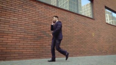 Akıllı telefonda konuşan duygusal gülümseyen genç adam. Heyecanlı işadamı cep telefonu konuşurken iyi haber duymak için mutlu.