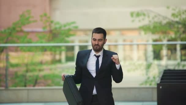 Aantrekkelijke man met een baard en de werkmap dansen in de straat — Stockvideo