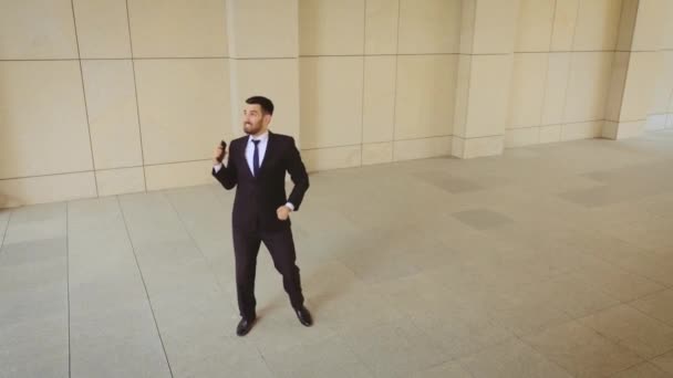 Onthullende shot van zakenman in zwart pak en rode stropdas dansen en springen rond in de stad. Hij is erg blij met de deal die hij maakte. — Stockvideo