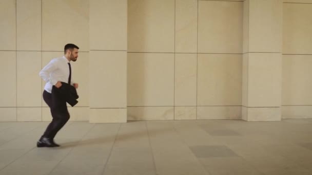A táskában egy utcai üzletember fut. Üzletember késve a találkozón. Sikeres férfi-öltöny jogging közelében modern épületben. Guy siet kinevezése. — Stock videók
