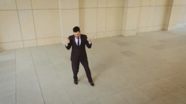 Siyah takım elbiseli ve kırmızı kravatlı işadamının şehirde dans eden ve zıplayan bir şekilde çekilmiş fotoğrafı. Yaptığı anlaşmadan çok memnun..