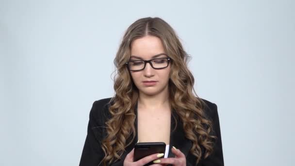 Сердита бізнес-леді на своєму телефоні на сірому фоні в студії, повільний рух — стокове відео