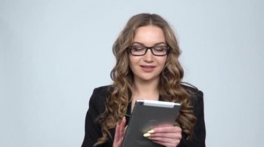 Stüdyoda gri arka planda gülümseme ile tabletinde mesajlaşma pensive iş kadını, yavaş hareket