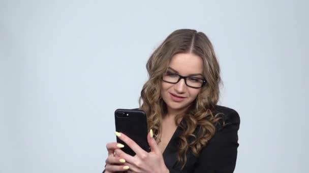 Sexy holka dělá na mobilním telefonu na šedém pozadí ve studiu, pomalý pohyb