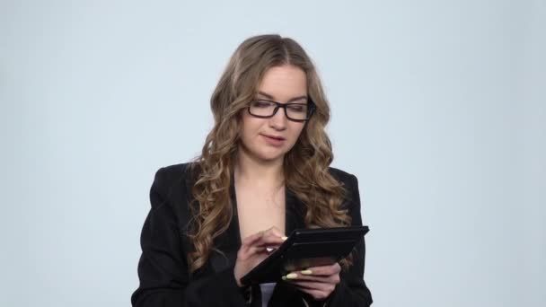 Woman office worker makes calculations on a calculator over gray background at studio, slow motion — Stock Video