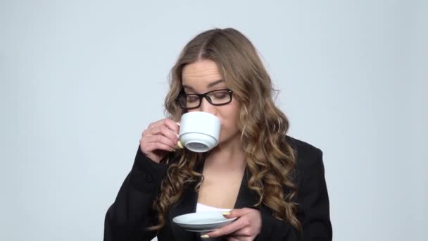 Работница офиса пьет кофе и улыбается, разговаривая с кем-то, замедленная съемка — стоковое видео