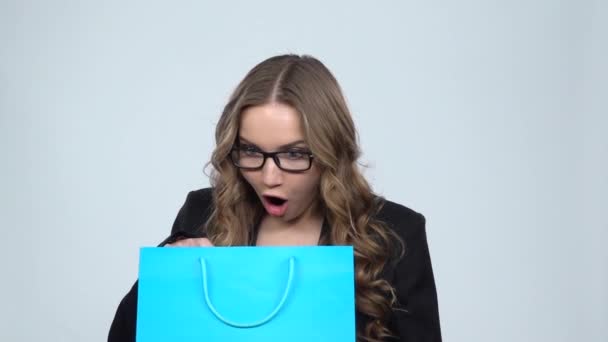 Девушка смотрит в синий пакет, а затем удивлен и очень радостно обнимает его, замедленной съемки — стоковое видео