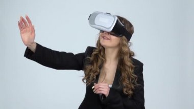 Gri arka planda kafasında sanal gerçeklik gözlüğü olan kadın, yavaş çekim.