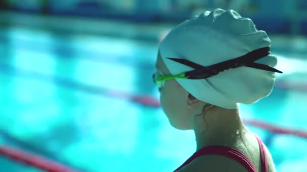 Портрет профессиональной девочки-подростка, которая плавает в очках, выходящих из бассейна — стоковое видео