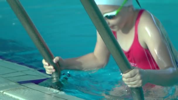 Vista lateral jovem nadadora sai da piscina interior com água azul, câmera lenta , — Vídeo de Stock