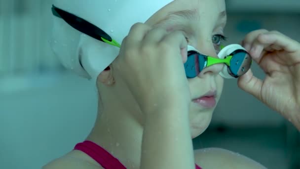 Teenager girl putting goggles and looking at camera in swimming pool, close up. — Stock Video