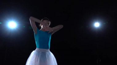 Beyaz etekli zarif balerin klasik bale elementleriyle dans ediyor. Kapat.