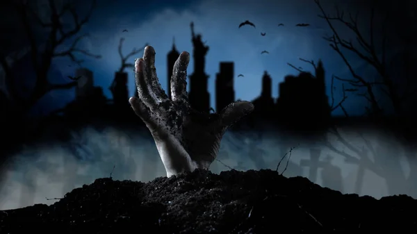 Spooky graveyard with zombie hand coming out of the ground