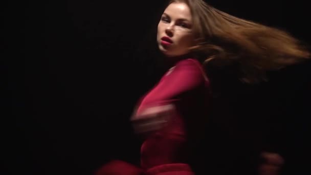 Girl in a red dress is dancing on a black background in the studio. Dolly shot. Slow motion — Stock Video