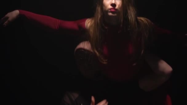 Guy et fille dansent avec des supports sur le fond noir sous les projecteurs dans un studio sombre. Mouvement lent — Video