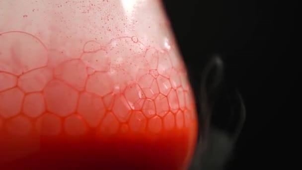 Closeup of dry ice bubbling in a glass with red blood on a black background. — Stock Video