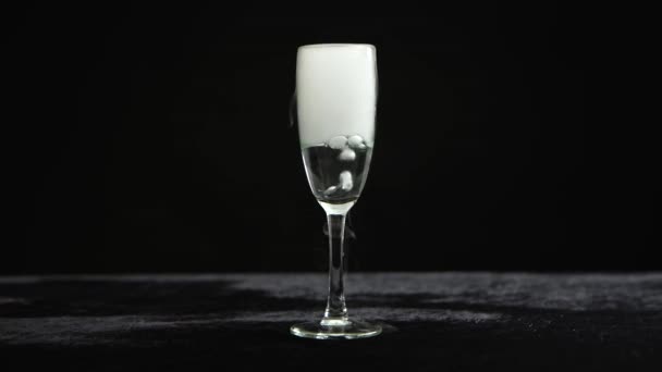 Dry ice bubbling in a glass of champagne at black background. — Stock Video