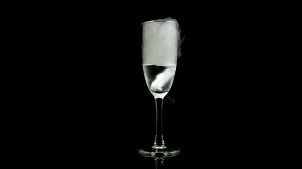 Dry ice bubbling in a glass of champagne at black background with a mirror image . — Stock Video