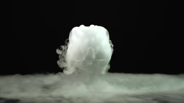 Siyah zemin üzerinde kuru buz etkisi olan konyak bardağı. — Stok video