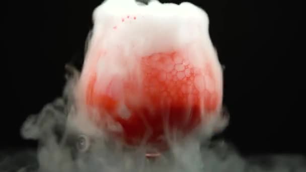 Droogijsbloed borrelend in een glas met rode verf op een zwarte achtergrond. Sluitingsdatum — Stockvideo