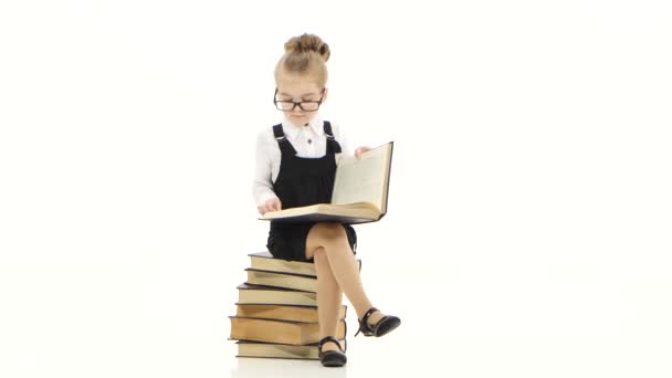 Clever little girl is reading big book on white background — Stock Video