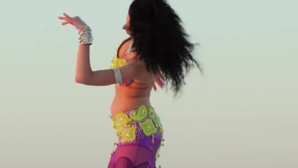 Брюнетка танцует против неба танец живота, она грациозна и утонченна — стоковое видео
