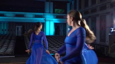 Grup genç yetenekli balerinler büyük salon sahnede modern bale dans. Kızlar oditoryuma bakıyor. Performans öncesi kostümlü prova.